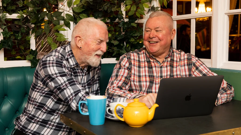 Two men looking at a laptop and laughing