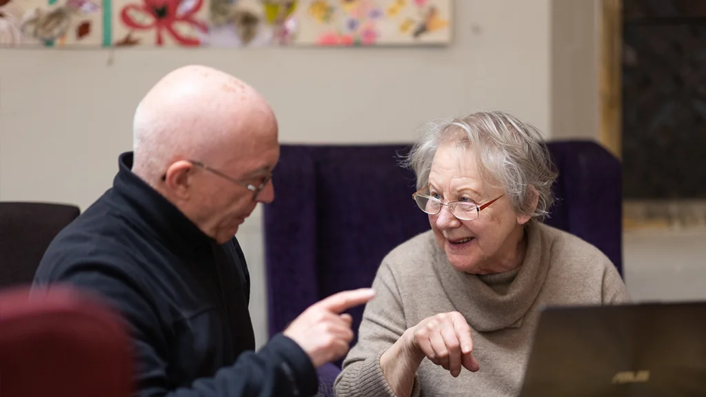 Two older people in front of a laptop